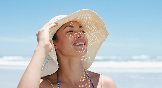 A woman smiling while wearing a hat for sun damage protection