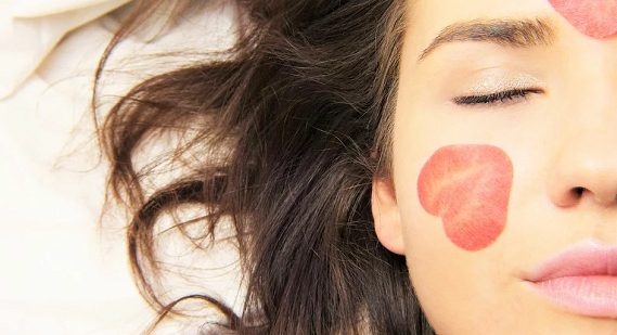Close up of a girl with thin strawberry slices on face